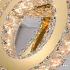 Intertwined gold and crystal rings with embedded LEDs create a sparkling, elegant chandelier.