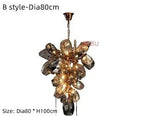Modern crystal chandelier with stainless steel and irregular glass clusters, integrated LED, emits warm light.
