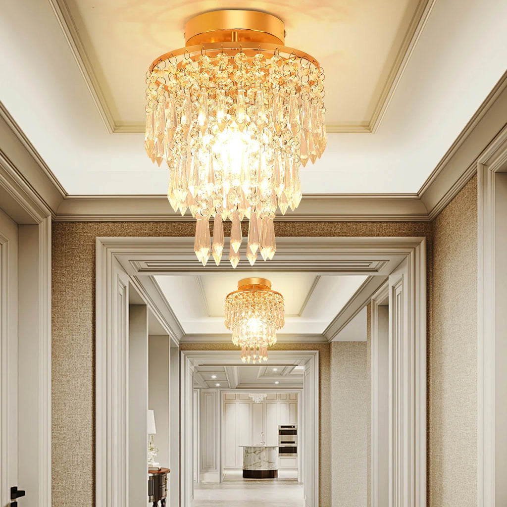Two Maison Ornate Modern Crystal Art Deco Chandeliers with gold stainless frames, warmly illuminated.