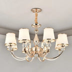 Luxury Baroque Crystal Chandelier with gold finish, six curved arms, white fabric lampshades.