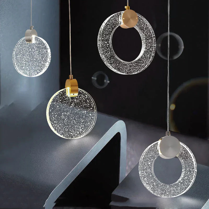 Four crystal pendant chandeliers by Maison Ornate with circular textured shades and metallic accents.