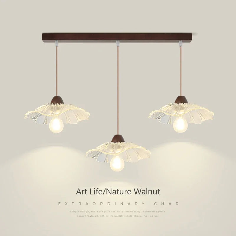 Flower-shaped clear glass pendant chandeliers with walnut-tone fixtures hang from a rectangular ceiling mount.