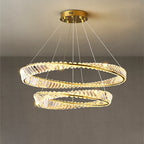 Gold crystal chandelier with two overlapping rings, suspended by wires, emits warm white light.