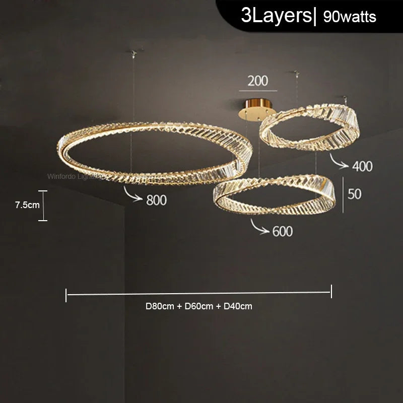 Three illuminated crystal-edged rings in varying sizes hang at different heights, forming a modern chandelier.