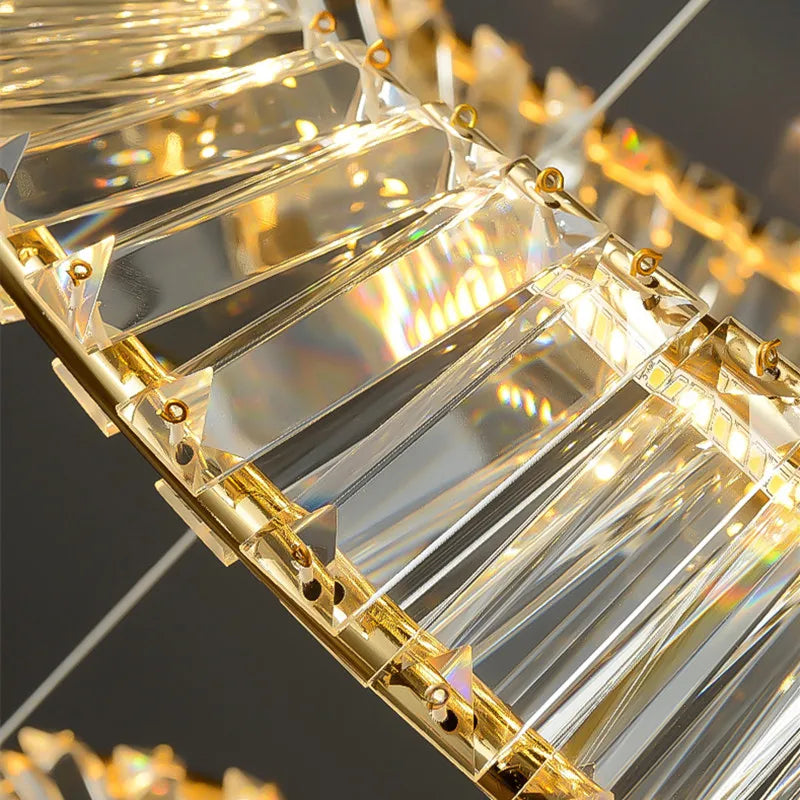 Close-up of Maison Ornate Modern Crystal Chandelier—curved gold frame, clear glass prisms, warm LED glow.