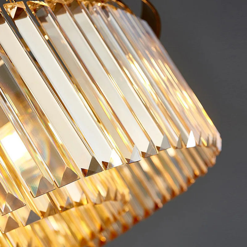 Luxurious spiral chandelier with gold-edged glass prisms reflecting warm yellow light, exuding elegance.