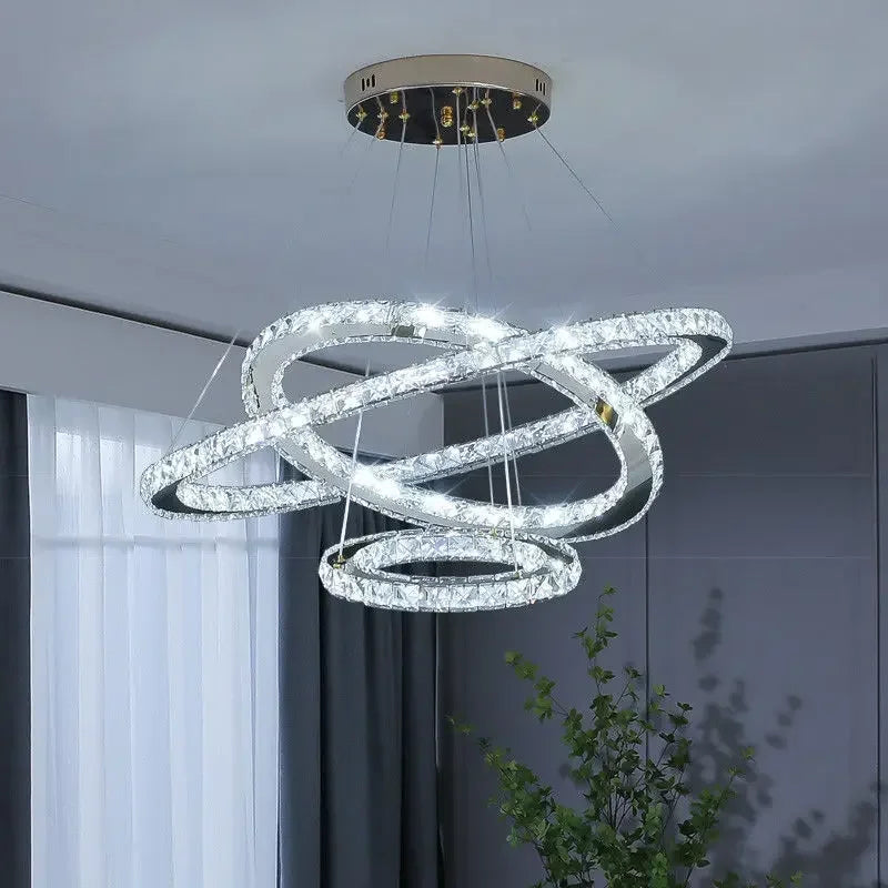 Maison Ornate Elegant Crystal Chandelier with three illuminated, interlocking rings suspended by wires.