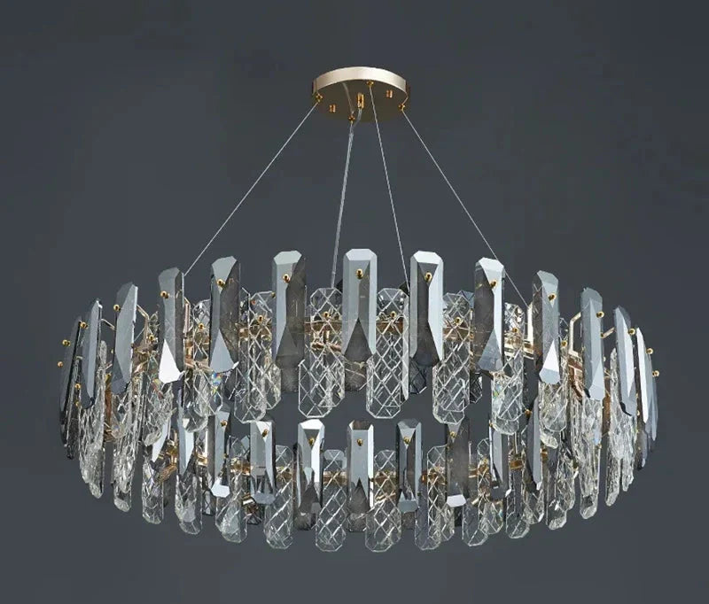 Oval chandelier with vertical crystals, metallic accents, four suspension wires, and a sleek central ring.