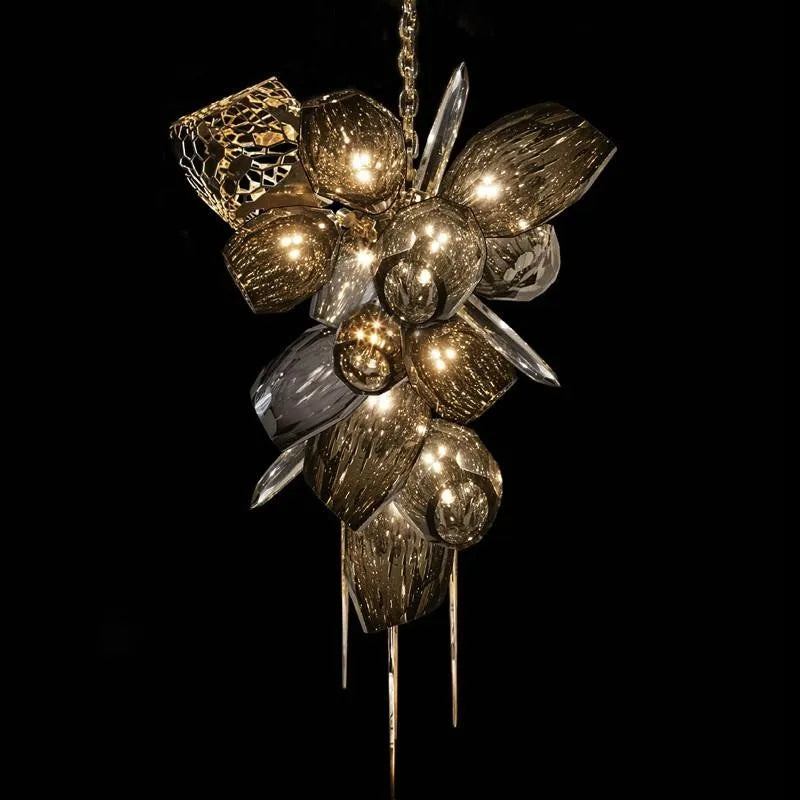 Abstract gold and metallic chandelier with crystal glass, leaf-like clusters and orb accents.
