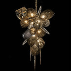 Abstract gold and metallic chandelier with crystal glass, leaf-like clusters and orb accents.