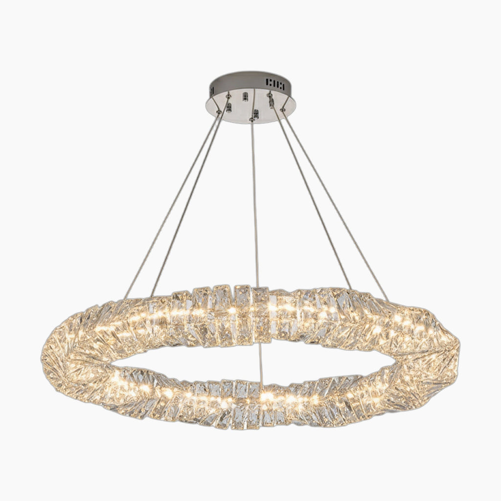 Circular chandelier with clear crystal segments, four cable suspension, metallic base, emits bright light.
