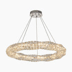Circular chandelier with clear crystal segments, four cable suspension, metallic base, emits bright light.