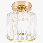 Gold-base chandelier with cylindrical vertical crystal prisms, warm glow, modern industrial design. Contemporary lighting.