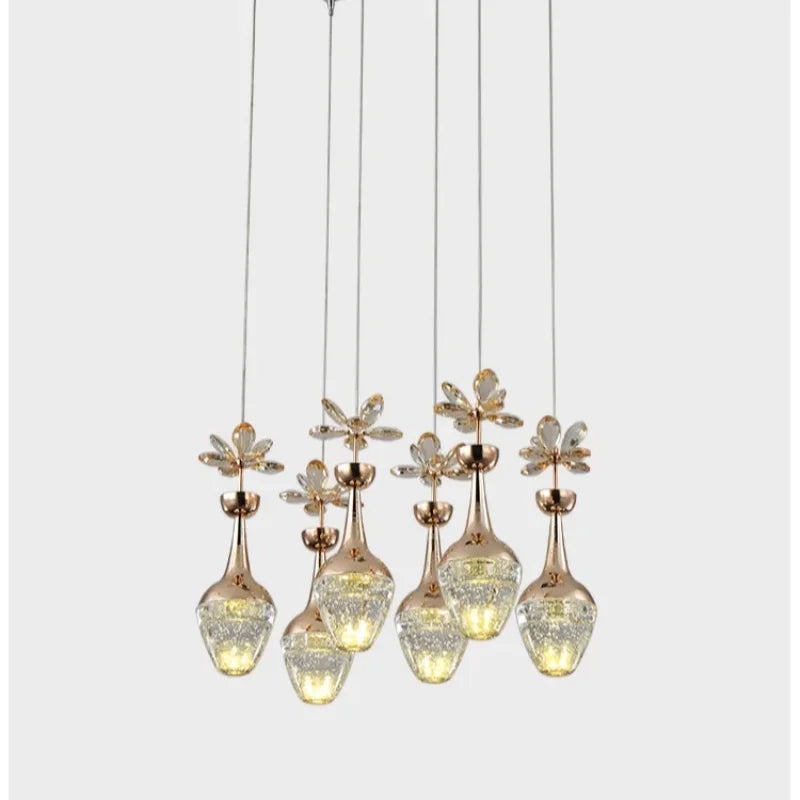 Six Maison crystal pendants with gold accents, clear flower glass shades, varying heights.