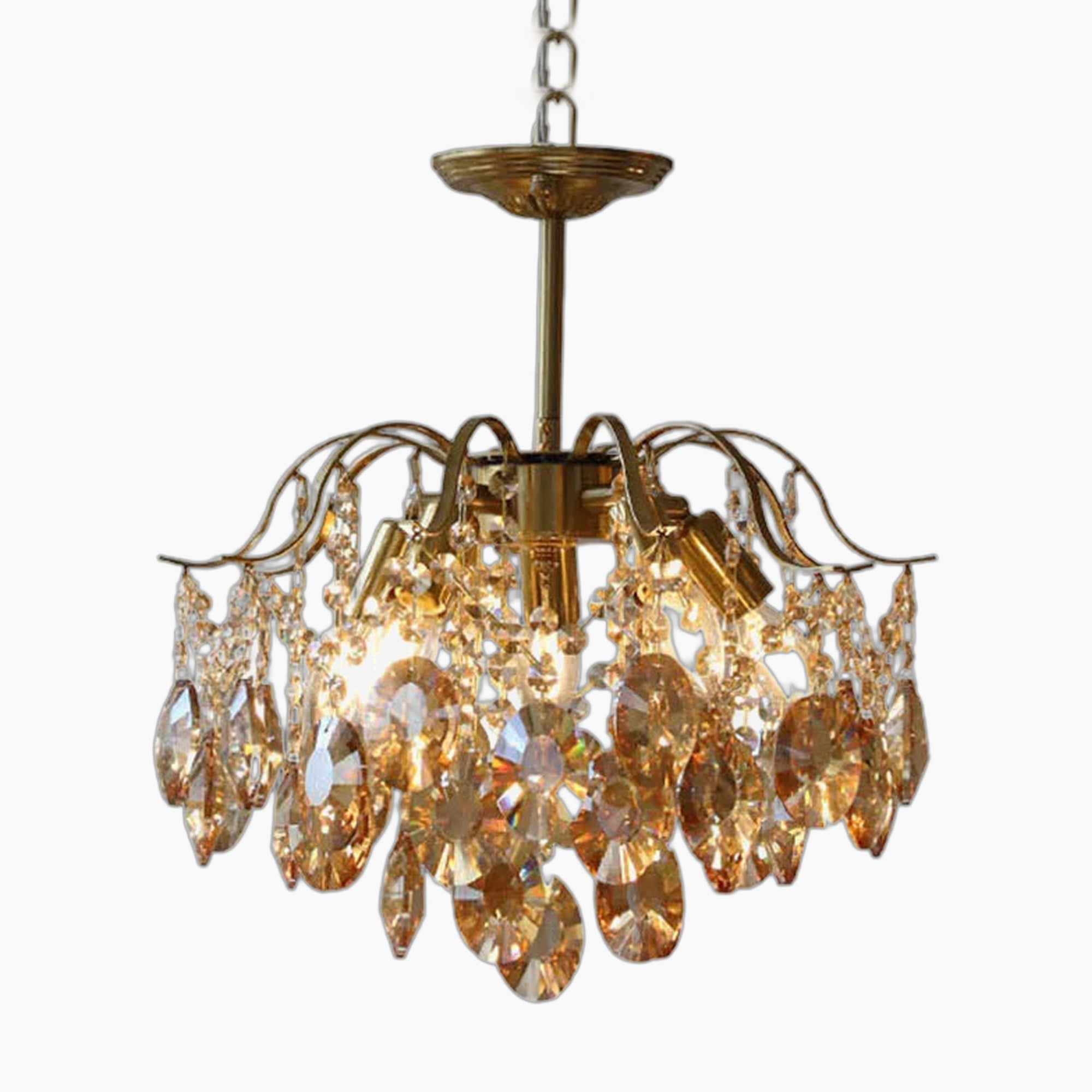Ornate vintage chandelier with metal arms, crystal pendants, and ceiling chain; elegant, classic design.