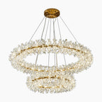 Dual gold LED rings with crystal accents suspended by wires, offering warm, adjustable chandelier lighting.
