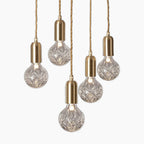 Pendant chandelier with five faceted glass bulbs, brass-toned sockets, and twisted cords for modern style.