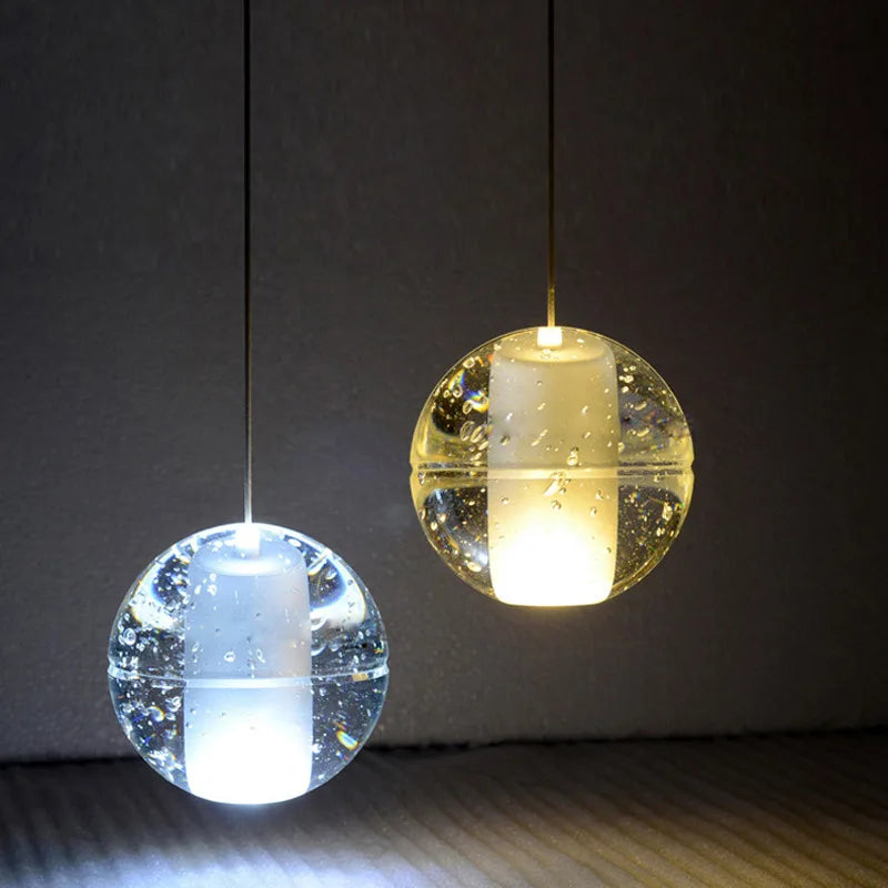 Pair of Maison Ornate crystal sphere chandeliers with rotating LEDs, clear globes, air bubbles, dual light tones.