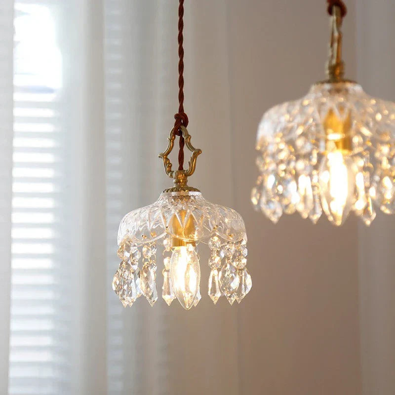Pair of ornate Nordic vintage crystal and brass pendant lights with glowing crystal lampshades.