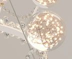 Transparent glass globe chandelier with LED lights, copper wires, and crystal detailing in crown shape.