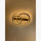 Modern crystal chandelier with two overlapping LED rings, stainless steel, emits warm golden light.