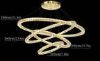 Four illuminated, interlocking gold rings form a modern crystal chandelier suspended from a round mount.