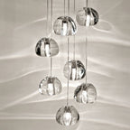 Eight rounded glass crystal pendant lights hang at different heights on slender cords, softly glowing.