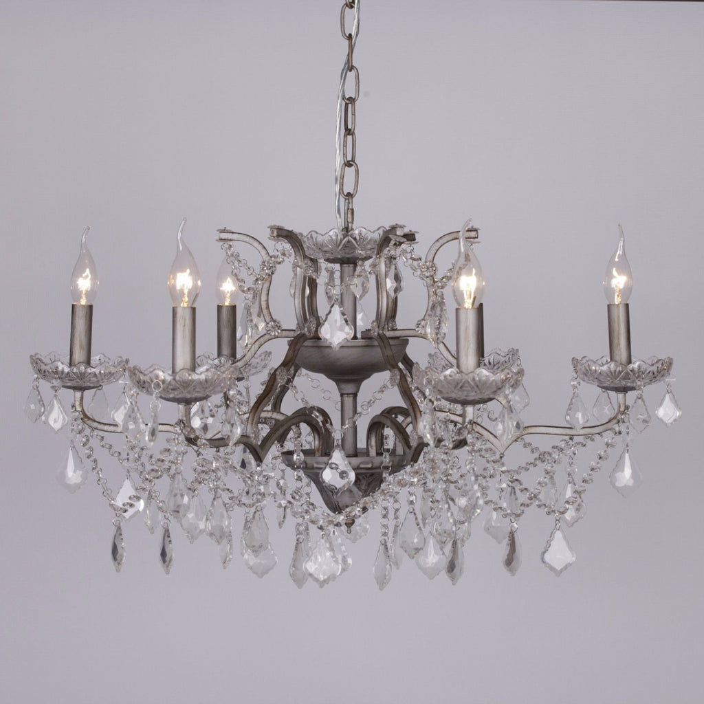 Ornate French style chandelier with six silver glass arms, candle bulbs, and crystal pendants.