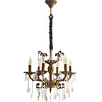 Brass chandelier with 12 ornate arms, candle-style bulbs, and crystal pendants, suspended by fabric chain.
