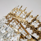 Close-up of Maison Ornate gold chandelier with intricate details and clear crystal pendants.
