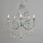 Five-arm polished chrome chandelier with sparkling crystal accents and candle-style bulbs for elegance.