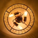 Close-up of gold 3-light crystal chandelier with exposed bulbs and metal accents, glowing warmly.
