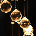 Maison Ornate Crystal Ball Chandelier features faceted glass balls on thin wires, warmly illuminated.