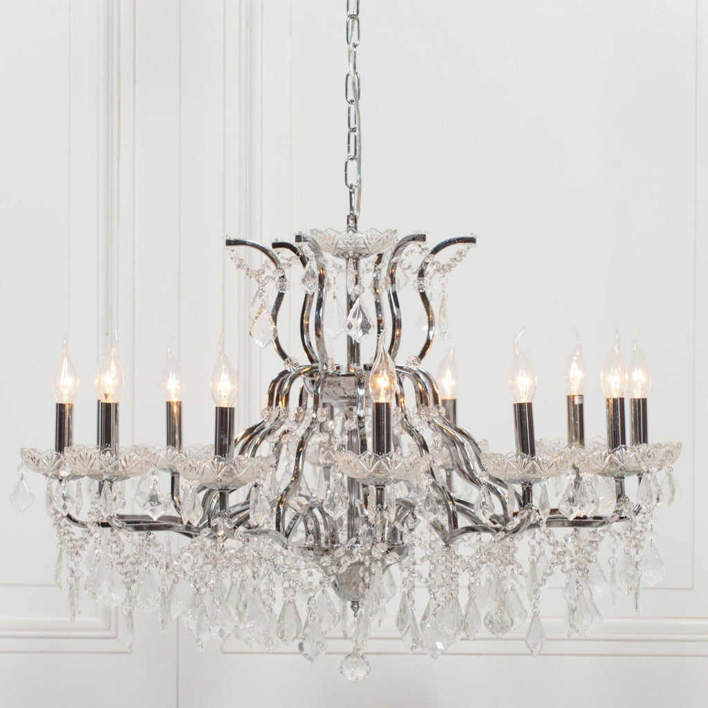 Ornate French chrome chandelier with 12 arms, candle bulbs, and hanging crystal prisms.