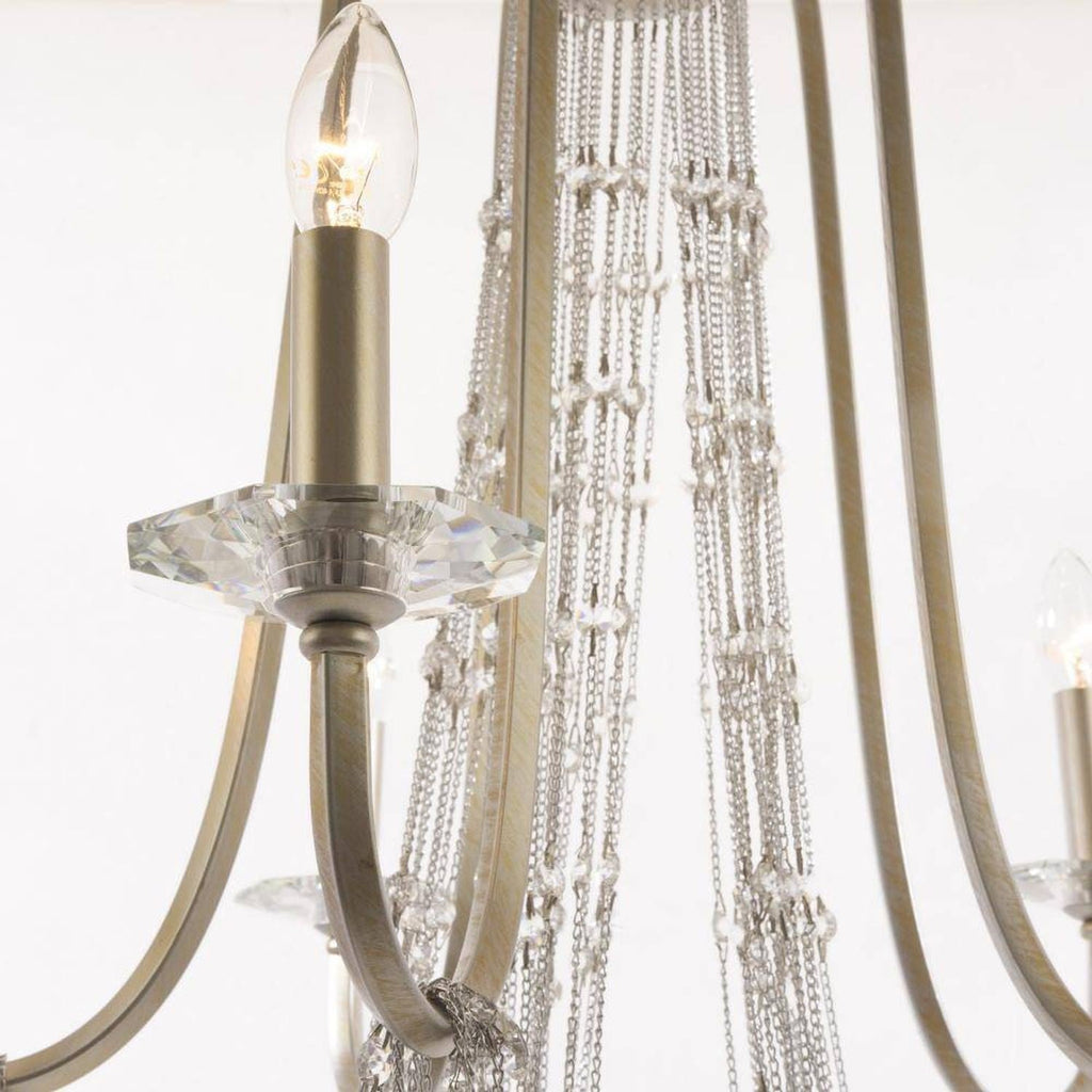 Maison Ornate Elegant chandelier with gold arms, candle-style bulbs, crystals, and faceted glass details.