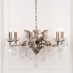 Maison Ornate French crystal chandelier with six silver arms, candle bulbs, ornate metalwork, hanging glass crystals.